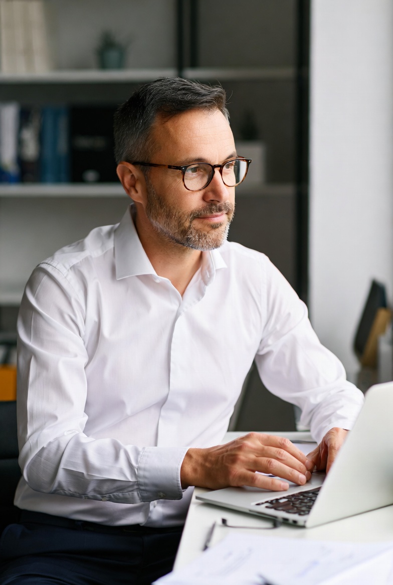 A founder closing a laptop at sunset, with a calm ocean and glowing async workflow dashboard in the background